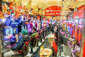 Osaka stad, Japan, 2023 - interieur van Japans flipperkast spellen winkel pakchinko met kleurrijk van LED lichten en mensen zitten en Speel zijn spellen aandachtig. pakchinko is de populair het gokken in Japan. foto