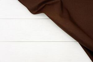 gerimpeld donker bruin kleding stof Aan rustiek wit hout plank achtergrond, met kopiëren ruimte. foto