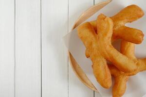 vader tong Gaan, Thais stijl Chinese crullers in houten bord Aan wit houten achtergrond. top visie met kopiëren ruimte. foto