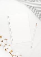 blanco wit spiraal notitieboekje met wit potlood Aan bed. foto