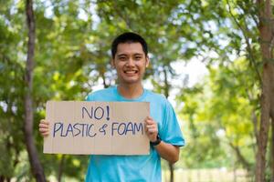 gelukkig jong Aziatisch studenten verschillend vrijwilligers houden een campagne teken voor schoonmaak in de park, de concept van milieu behoud Aan wereld milieu dag, recyclen, liefdadigheid voor duurzaamheid. foto