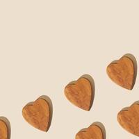 creatief patroon samenstelling gemaakt met houten harten Aan pastel beige achtergrond met kopiëren ruimte. minimaal concept. modieus liefde patroon achtergrond idee. vlak leggen. foto