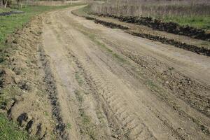 aarde weg geëgaliseerd door een nivelleermachine. weg in dorp foto