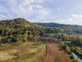 luchtfoto van boerderij die in de herfst bluffs afwerkt met natuurlijke kleuren en blauwe lucht geoogste maïsveld open omgeving foto
