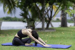 slank meisje Speel yoga Aan de gazon Bij de parkeren, ontspannen in natuur, aziatisch meisjes liefde Gezondheid beoefenen yoga foto