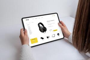 meisje winkels online voor koptelefoon, gadgets, en apparaten Aan een modern e-commerce webpagina gebruik makend van een tablet. naadloos tech browsen voor de laatste apparaten en accessoires foto