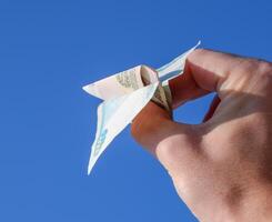 denominaties van Russisch geld, gevouwen in de vliegtuig tegen de blauw lucht in hand- foto