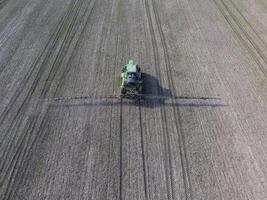 trekker met scharnierend systeem van sproeien pesticiden. bemesting met een tractor, in de het formulier van een aërosol, Aan de veld- van winter tarwe. foto