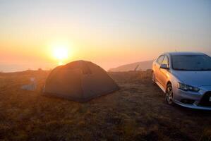 dageraad over- de zee, zonsopkomst over- de tent. in de buurt de tent is een auto foto