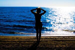 silhouet van een mooi meisje figuur Aan de achtergrond van de zee Bij zonsondergang foto