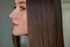 portret van een mooi vrouw met lang bruin Rechtdoor haar- in een schoonheid salon. foto