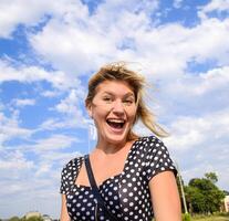 lachend blond meisje tegen de lucht met wolken foto