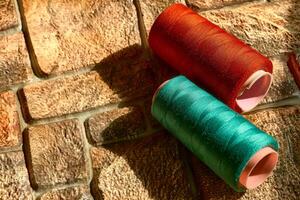 twee spoelen van naaien draad.kleermaker. smaragd, rood kleur foto