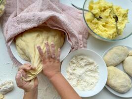 de handen van kind kneden de deeg voor maken taarten Aan wit tafel, top visie. foto