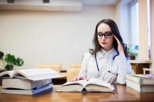 een medisch leerling voor studieboeken. de studie van chirurgie door een mooi meisje in de bibliotheek foto