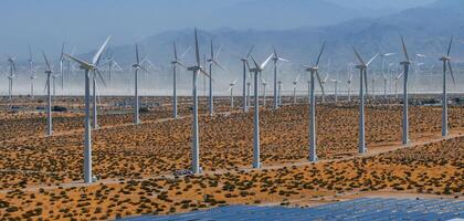 hernieuwbaar energie wind boerderij in dor woestijn landschap met blauw lucht, bergen, en dun vegetatie foto