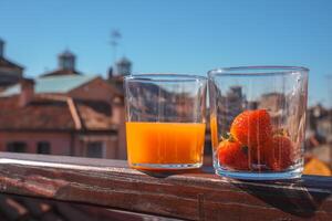 stad visie balkon elegant oranje sap en aardbeien met uitzicht iconisch Venetiaanse oriëntatiepunten foto