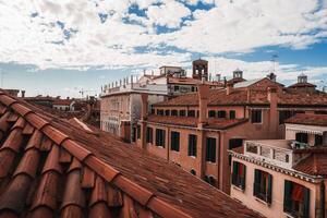 expansief Venetië stadsgezicht met traditioneel gebouwen en daken onder bewolkt lucht. foto