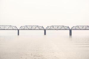 spoorweg truss brug over- een breed rivier- in mist foto