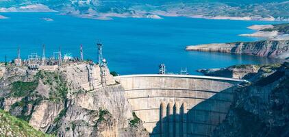 bovenste een deel van reusachtig boog dam van de hydro-elektrisch macht station en de elektrisch onderstation in een hoog berg Ravijn, de chirkeyskaya hpp in dagestan foto