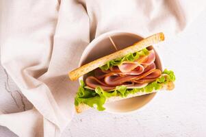 dichtbij omhoog van belegd broodje met ham, kaas en ui in een kom Aan de tafel top visie foto