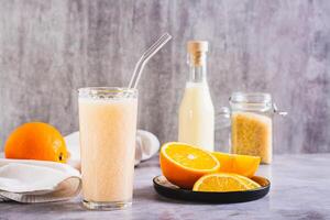vegetarisch smoothie gemaakt van rijst- melk en oranje in een glas Aan de tafel foto