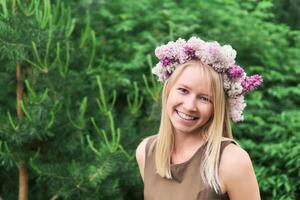 meisje vrouw in een bloemen krans van lila bloemen Aan een natuurlijk achtergrond buitenshuis foto