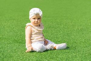 baby kleuter zittend Aan een groen gazon foto