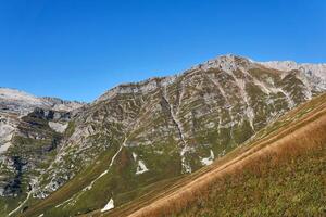 zonnig hoge berg hellingen met alpine weiden en stroken van geologisch lagen - sporen van monteren vissen in de Kaukasus foto