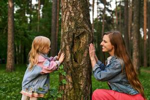 vrouw spelen met een kind in de Woud, schuilplaats achter een boom foto