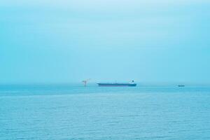 mistig zeegezicht met een tanker in de buurt een olie terminal gelegen ver uit naar zee foto