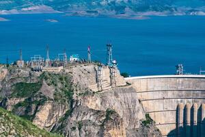 bovenste een deel van reusachtig boog dam van de hydro-elektrisch macht station en de elektrisch onderstation in een hoog berg Ravijn, de chirkeyskaya hpp in dagestan foto