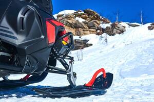 sneeuwscooter in de voorgrond tegen een wazig berg winter landschap foto