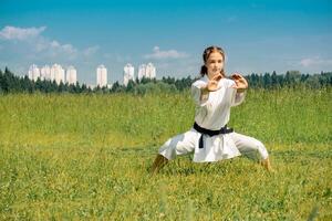 tiener meisje beoefenen karate kihon kata buitenshuis in kiba-dachi houding foto
