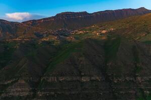 berg landschap met een dorp Aan een helling onder een reusachtig rotsachtig nok, chok in dagestan foto