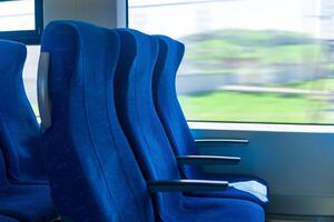 interieur van forens passagier trein auto, rij van stoelen en een bewegingsonscherp landschap buiten de venster foto