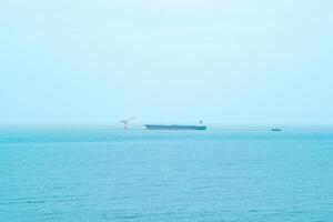 mistig zeegezicht met een tanker in de buurt een olie terminal gelegen ver uit naar zee foto