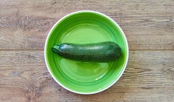 groen courgette squash met gevormde huid Aan een groen bord Aan een houten tafelblad foto