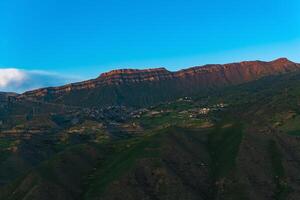 berg landschap met een dorp Aan een helling onder een reusachtig rotsachtig nok, chok in dagestan foto