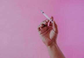 spuit, medisch injectie in hand, geneeskunde plastic vaccinatie uitrusting met naald- geïsoleerd Aan roze achtergrond. foto