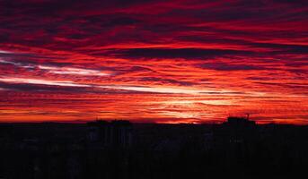 de rood oranje lucht tegen de achtergrond van de avond stad. mooi zonsondergang. selectief focus. lawaai. foto