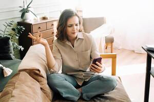 digitaal frustratie. perplex en woedend jong vrouw ontmoetingen problemen gedurende video telefoontje of online bestellen in haar leven kamer. technologisch uitdagingen en emotioneel angst. foto