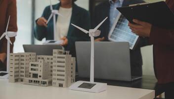 detailopname Bij tablet, ingenieurs richten Bij tablet met hun handen. naar gezamenlijk ontwerp de gebruik van hernieuwbaar energie met wind en zonne- energie. concept van gebruik makend van hernieuwbaar energie. foto