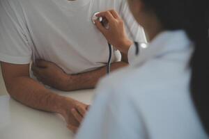 jong dokter is gebruik makend van een stethoscoop luister naar de hartslag van de geduldig. schot van een vrouw dokter geven een mannetje geduldig een controleren omhoog foto