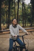 gelukkig Aziatisch jong vrouw wandelen en rijden fiets in park, straat stad haar glimlachen gebruik makend van fiets van vervoer, eco vriendelijk, mensen levensstijl concept. foto