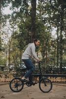 gelukkig Aziatisch jong vrouw wandelen en rijden fiets in park, straat stad haar glimlachen gebruik makend van fiets van vervoer, eco vriendelijk, mensen levensstijl concept. foto