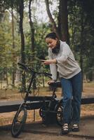 gelukkig Aziatisch jong vrouw wandelen en rijden fiets in park, straat stad haar glimlachen gebruik makend van fiets van vervoer, eco vriendelijk, mensen levensstijl concept. foto