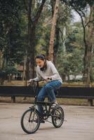 gelukkig Aziatisch jong vrouw wandelen en rijden fiets in park, straat stad haar glimlachen gebruik makend van fiets van vervoer, eco vriendelijk, mensen levensstijl concept. foto
