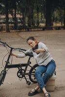 gelukkig Aziatisch jong vrouw wandelen en rijden fiets in park, straat stad haar glimlachen gebruik makend van fiets van vervoer, eco vriendelijk, mensen levensstijl concept. foto