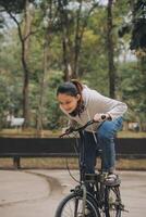 gelukkig Aziatisch jong vrouw wandelen en rijden fiets in park, straat stad haar glimlachen gebruik makend van fiets van vervoer, eco vriendelijk, mensen levensstijl concept. foto